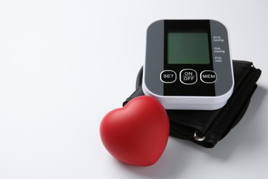 Photo of Blood pressure measuring device and squeeze heart on white background, closeup. Space for text