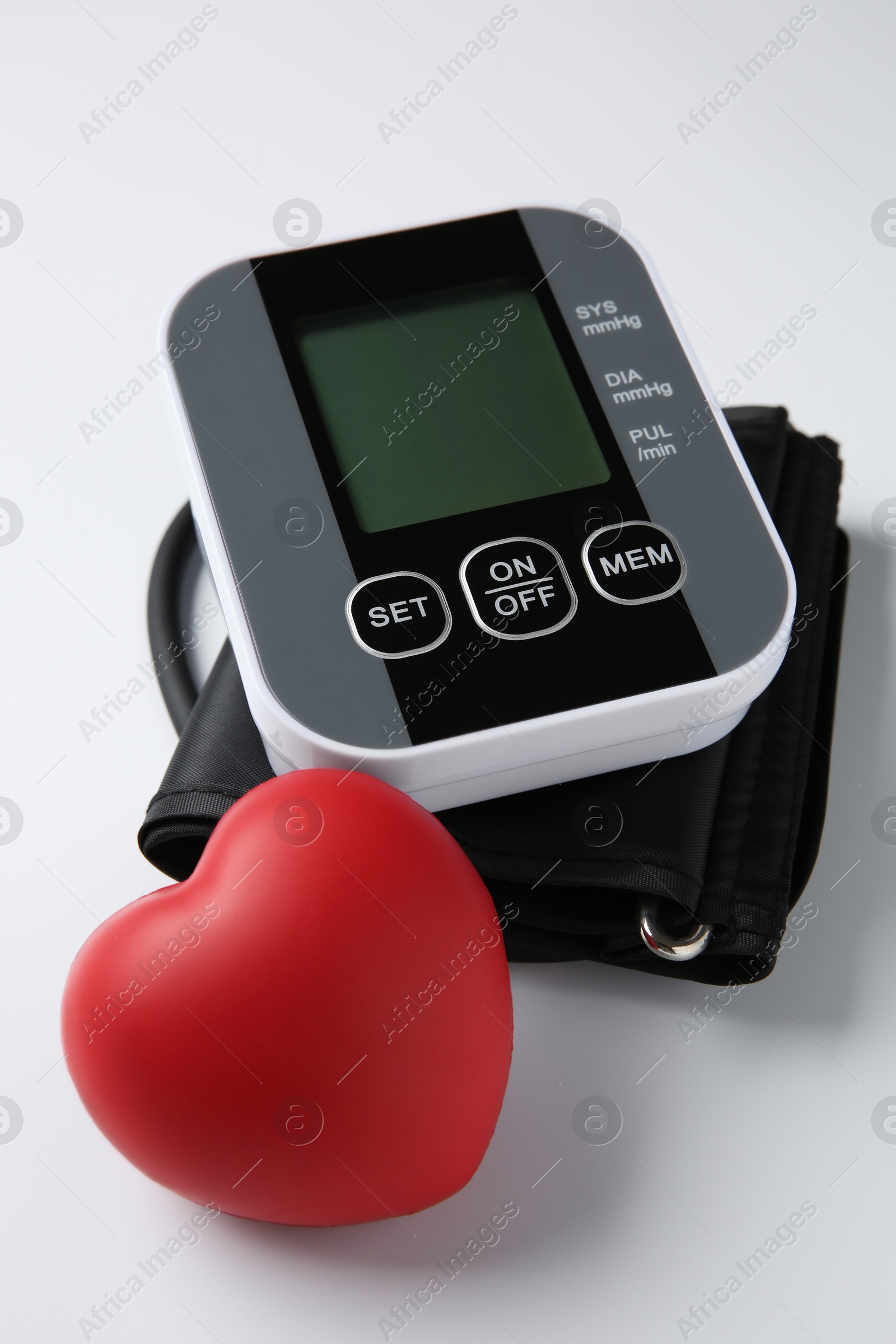 Photo of Blood pressure measuring device and squeeze heart on white background, closeup