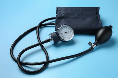 Photo of Blood pressure measuring device on light blue background, closeup