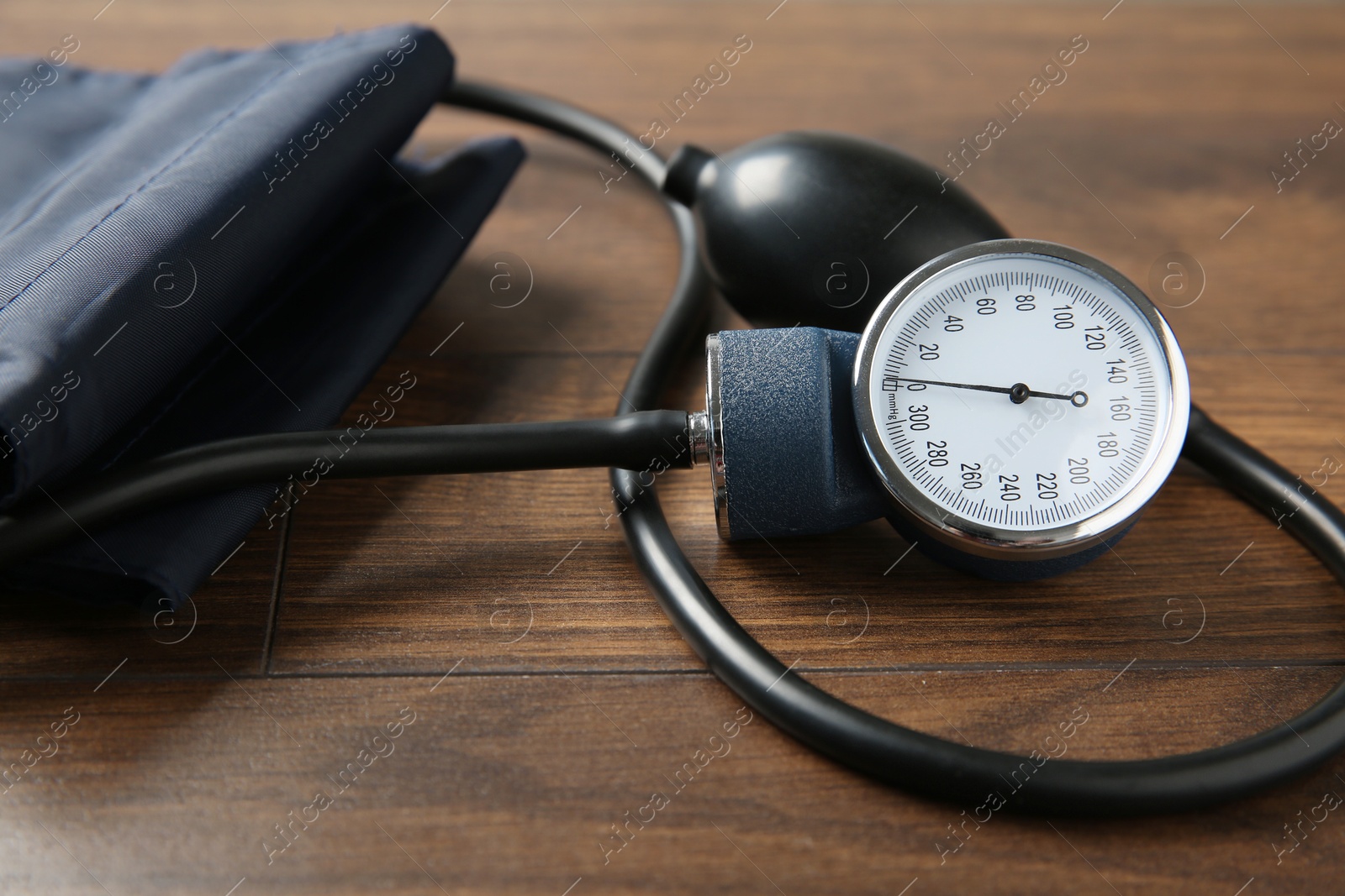 Photo of Blood pressure measuring device on wooden table, closeup