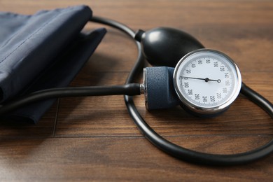 Photo of Blood pressure measuring device on wooden table, closeup