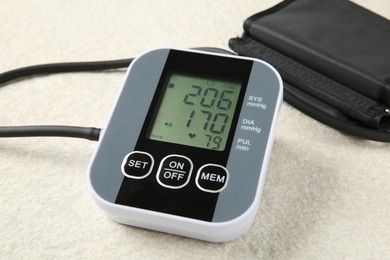 Photo of Blood pressure measuring device on light textured background, closeup