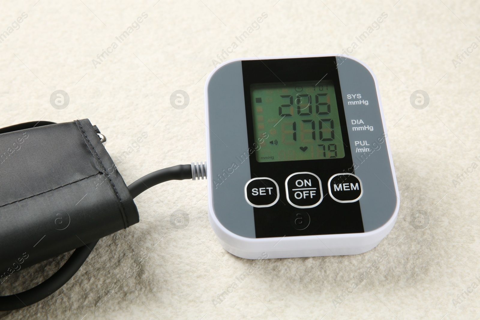 Photo of Blood pressure measuring device on light textured background, closeup