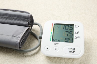 Photo of Blood pressure measuring device on light textured background, closeup