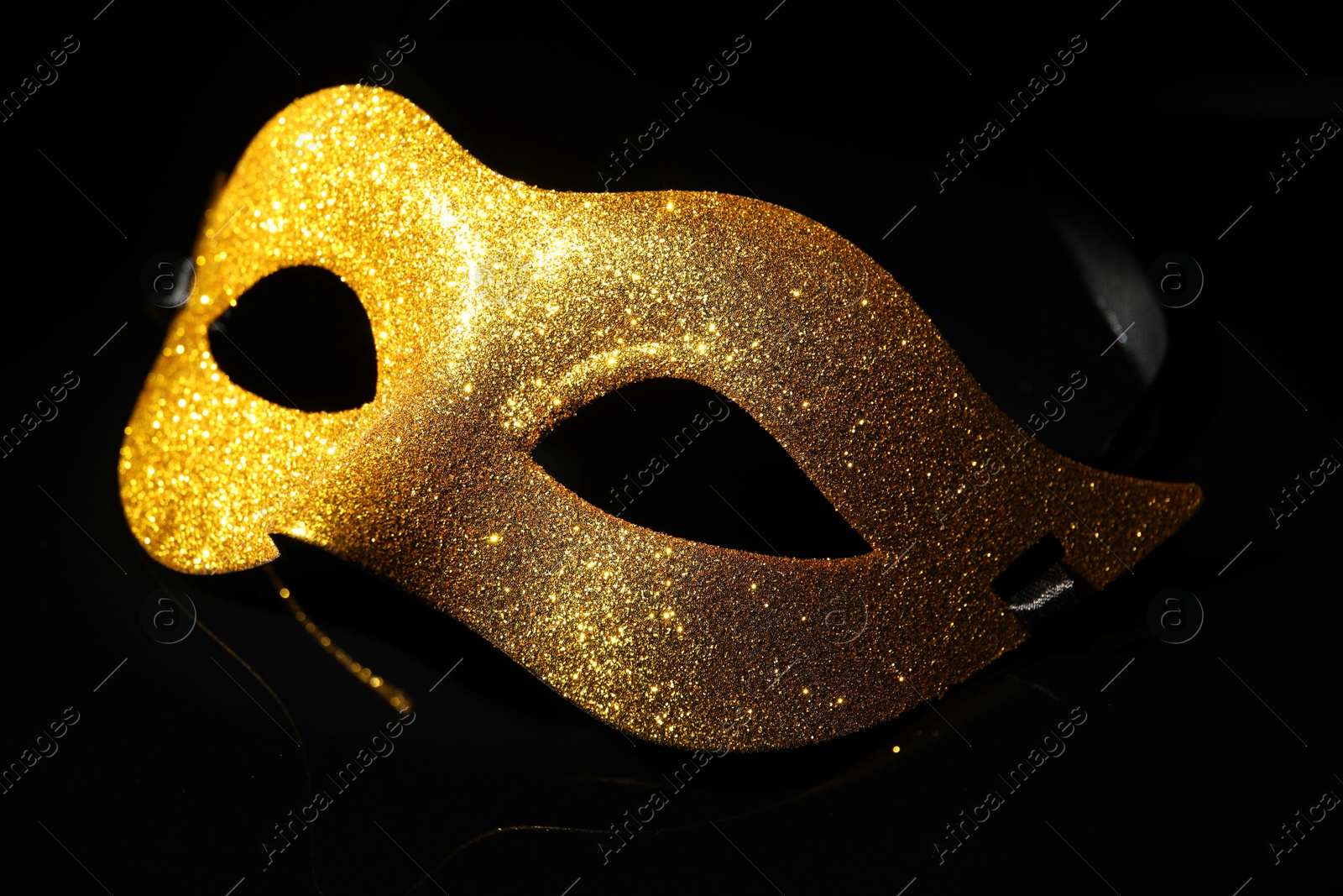 Photo of Beautiful golden carnival mask on black background, closeup