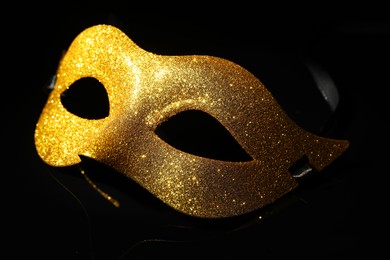 Photo of Beautiful golden carnival mask on black background, closeup