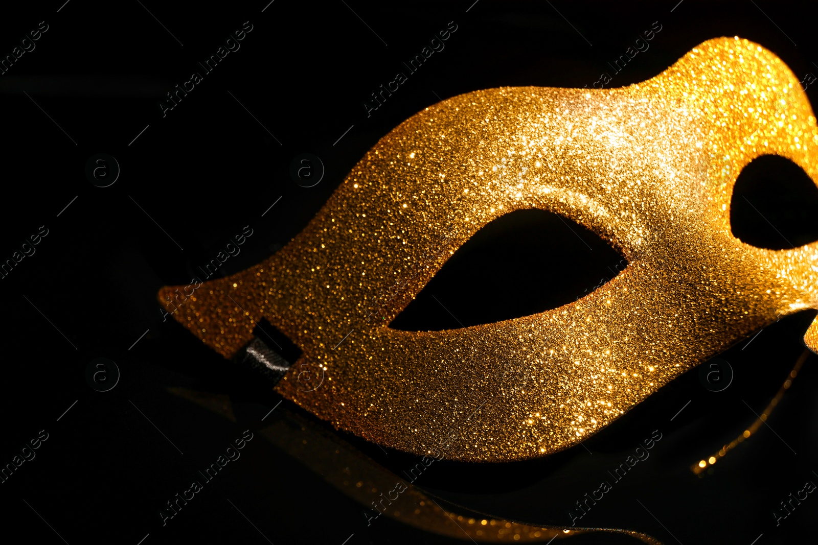 Photo of Beautiful golden carnival mask on black background, closeup