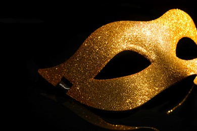 Photo of Beautiful golden carnival mask on black background, closeup