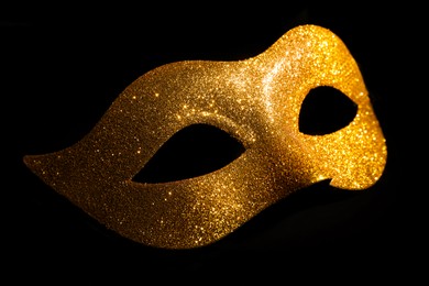 Photo of Beautiful golden carnival mask on black background, closeup