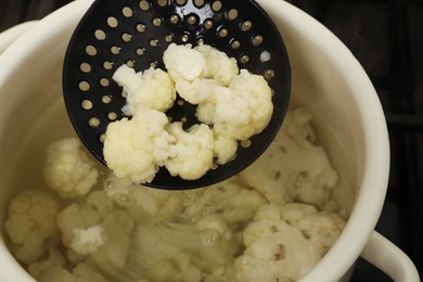 Photo of Taking boiled cauliflower from pot with skimmer, closeup