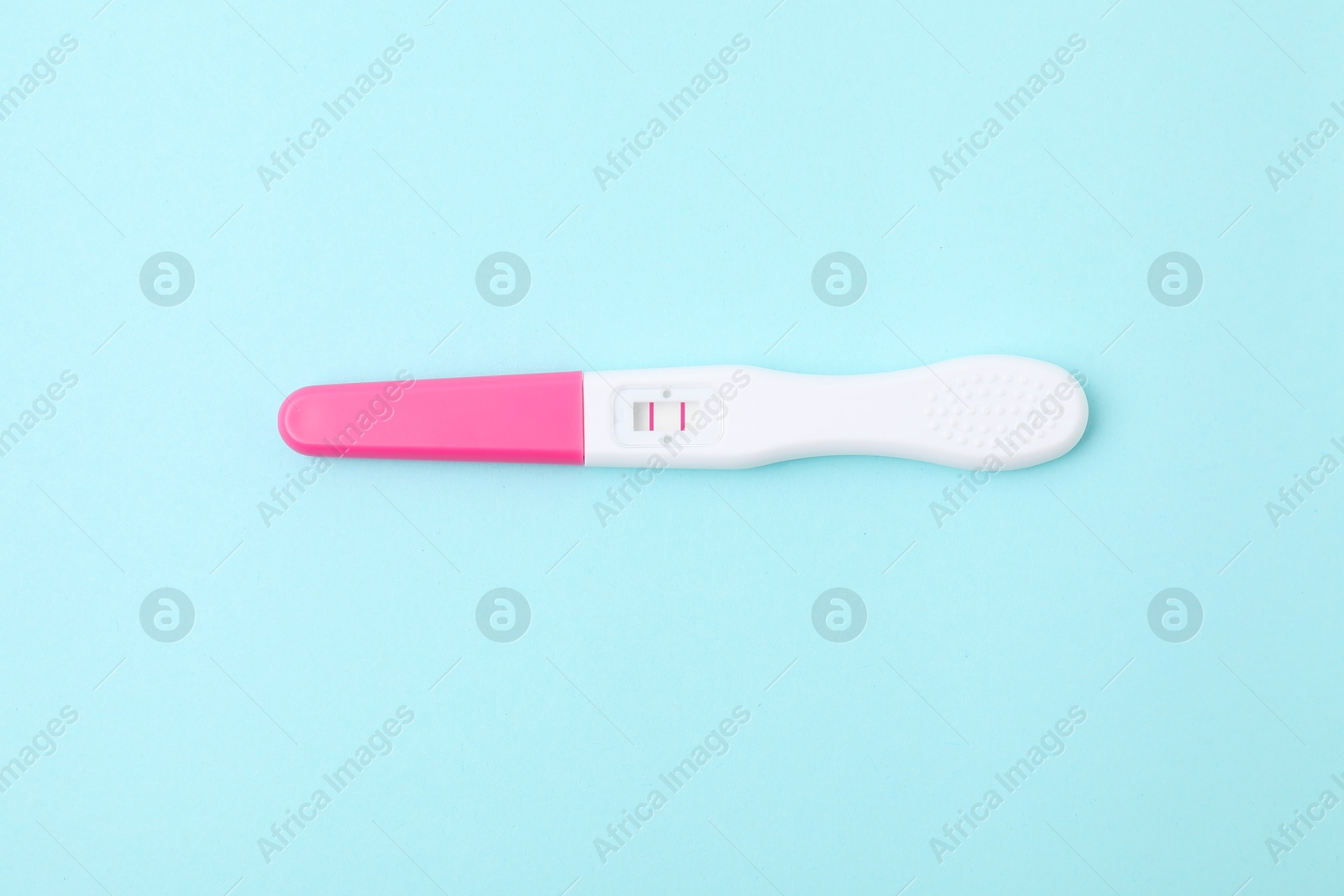 Photo of One pregnancy test on light blue background, above view