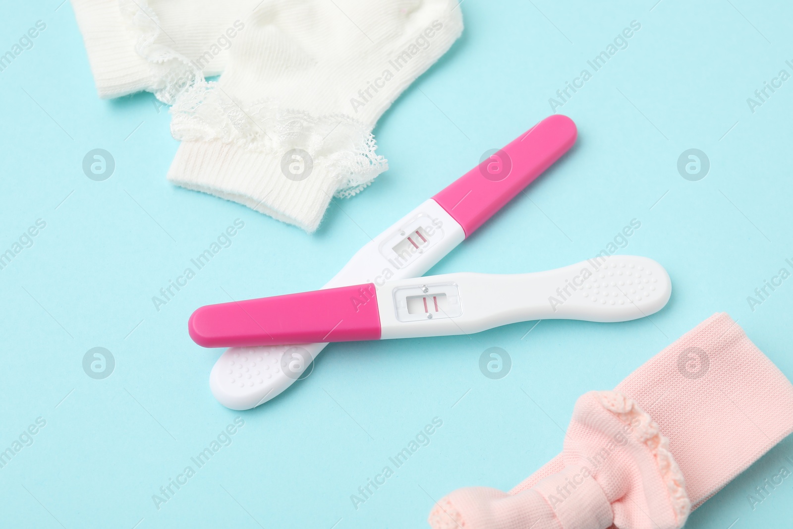 Photo of Pregnancy tests and socks on light blue background