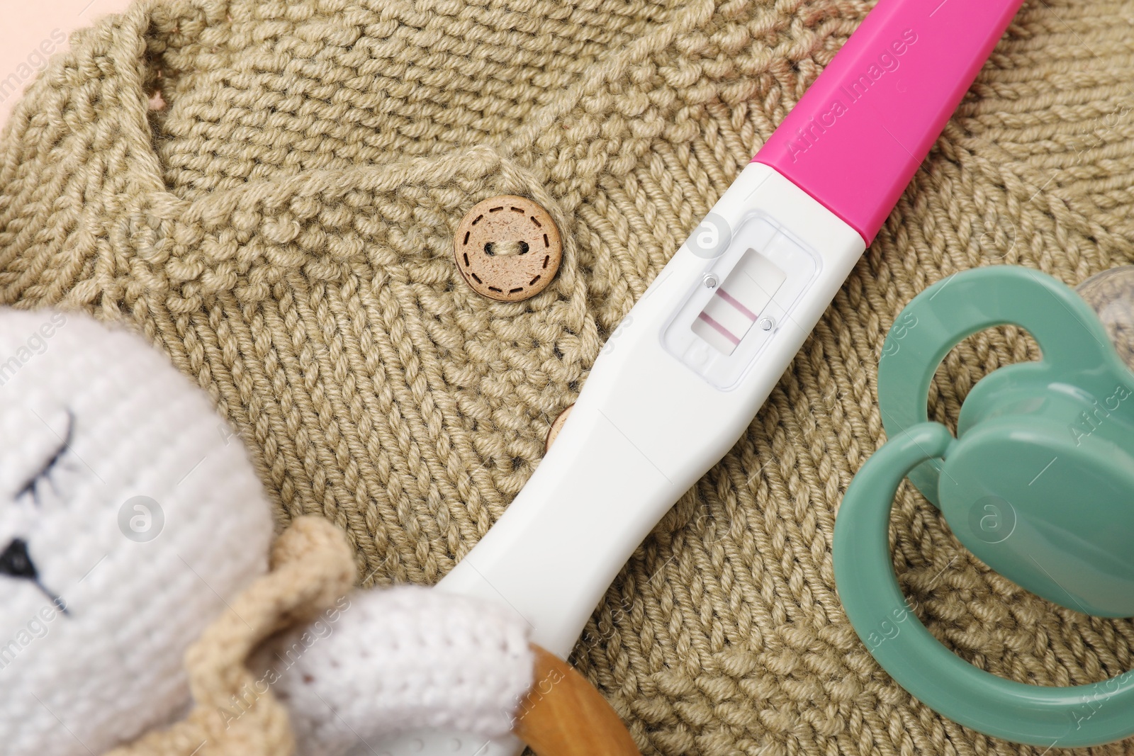 Photo of Pregnancy test, rattle, baby clothes and pacifier, closeup