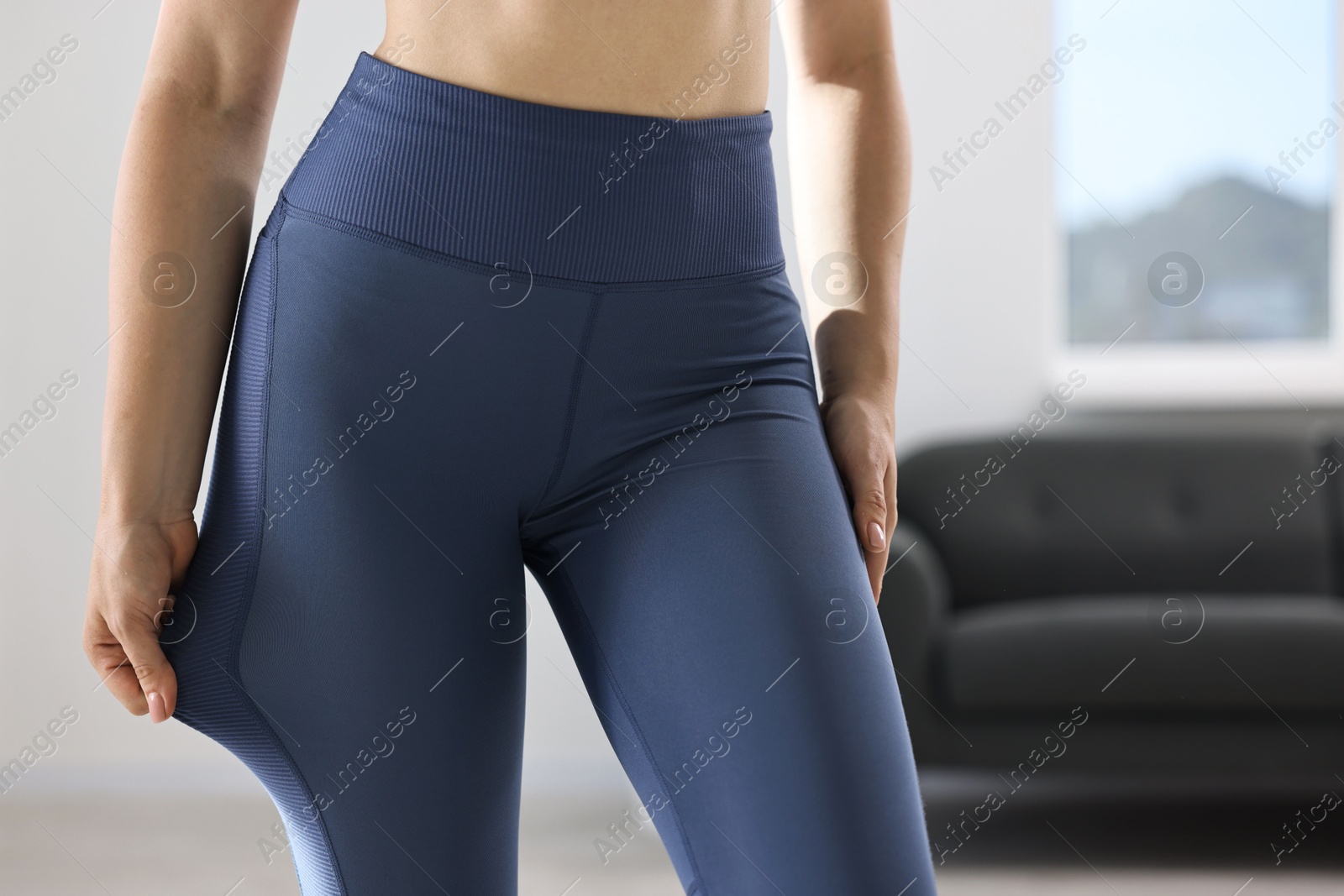 Photo of Woman wearing blue sports leggings indoors, closeup