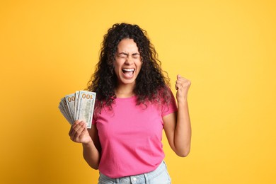 Happy woman with dollar banknotes on yellow background