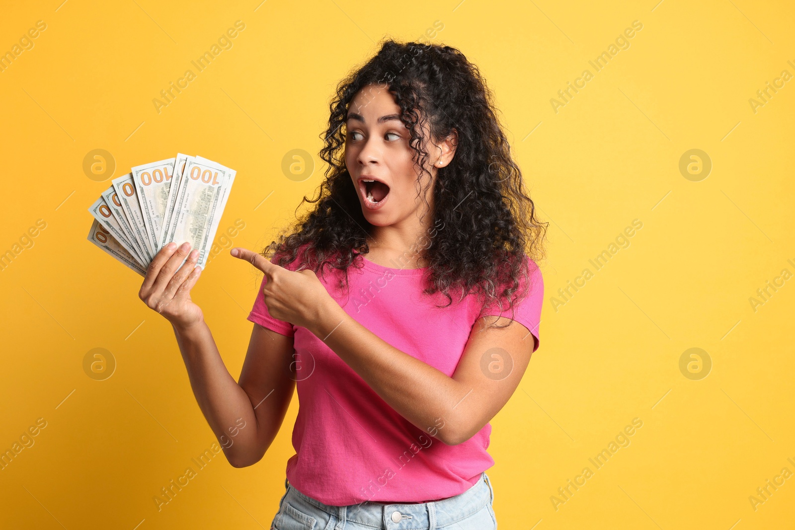 Photo of Shocked woman with dollar banknotes on yellow background