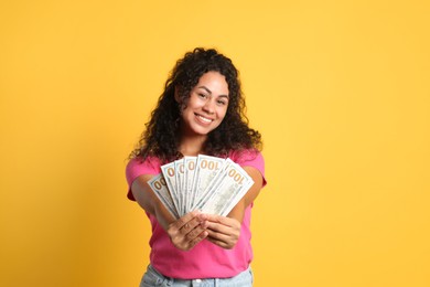 Photo of Happy woman with dollar banknotes on yellow background