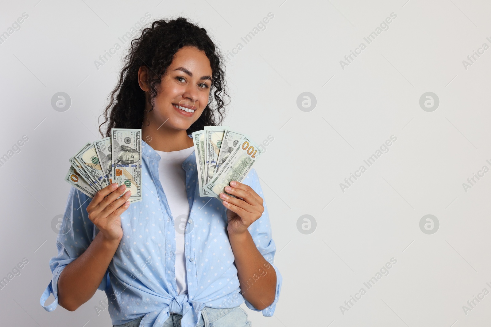 Photo of Happy woman with dollar banknotes on light grey background, space for text