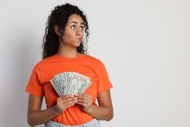 Woman with dollar banknotes on light grey background, space for text