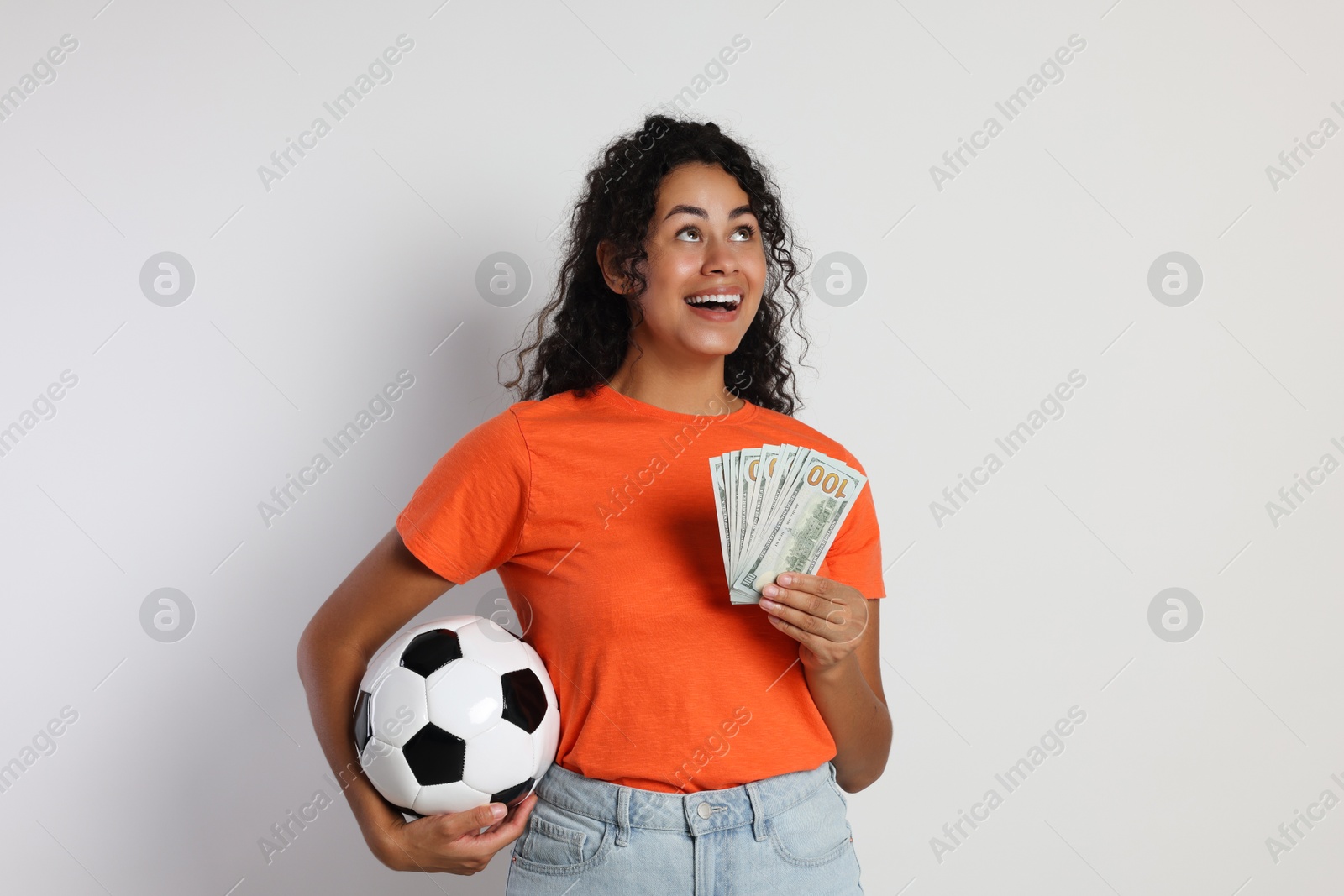 Photo of Happy woman with money and soccer ball on light grey background