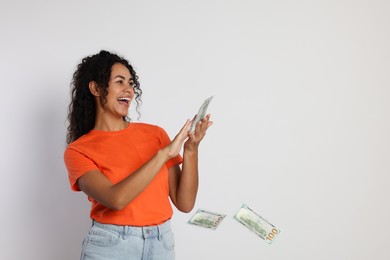 Photo of Happy woman throwing money on light grey background, space for text