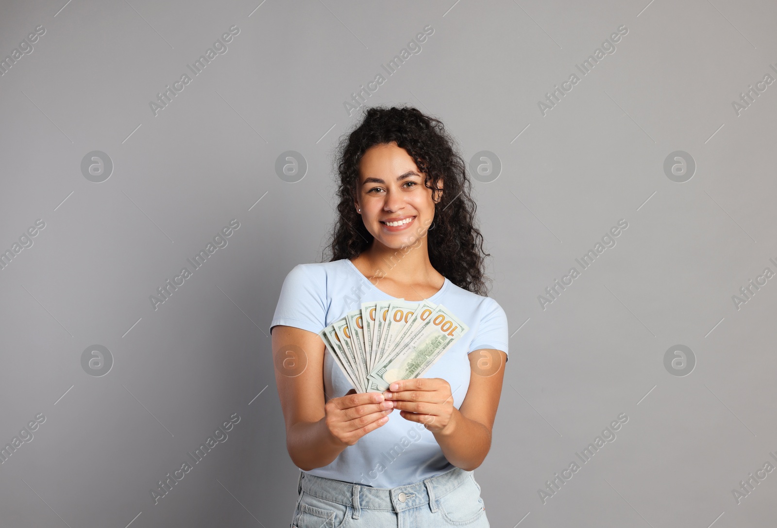 Photo of Happy woman with dollar banknotes on grey background