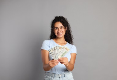 Happy woman with dollar banknotes on grey background