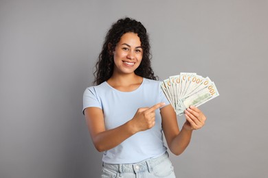 Happy woman with dollar banknotes on grey background