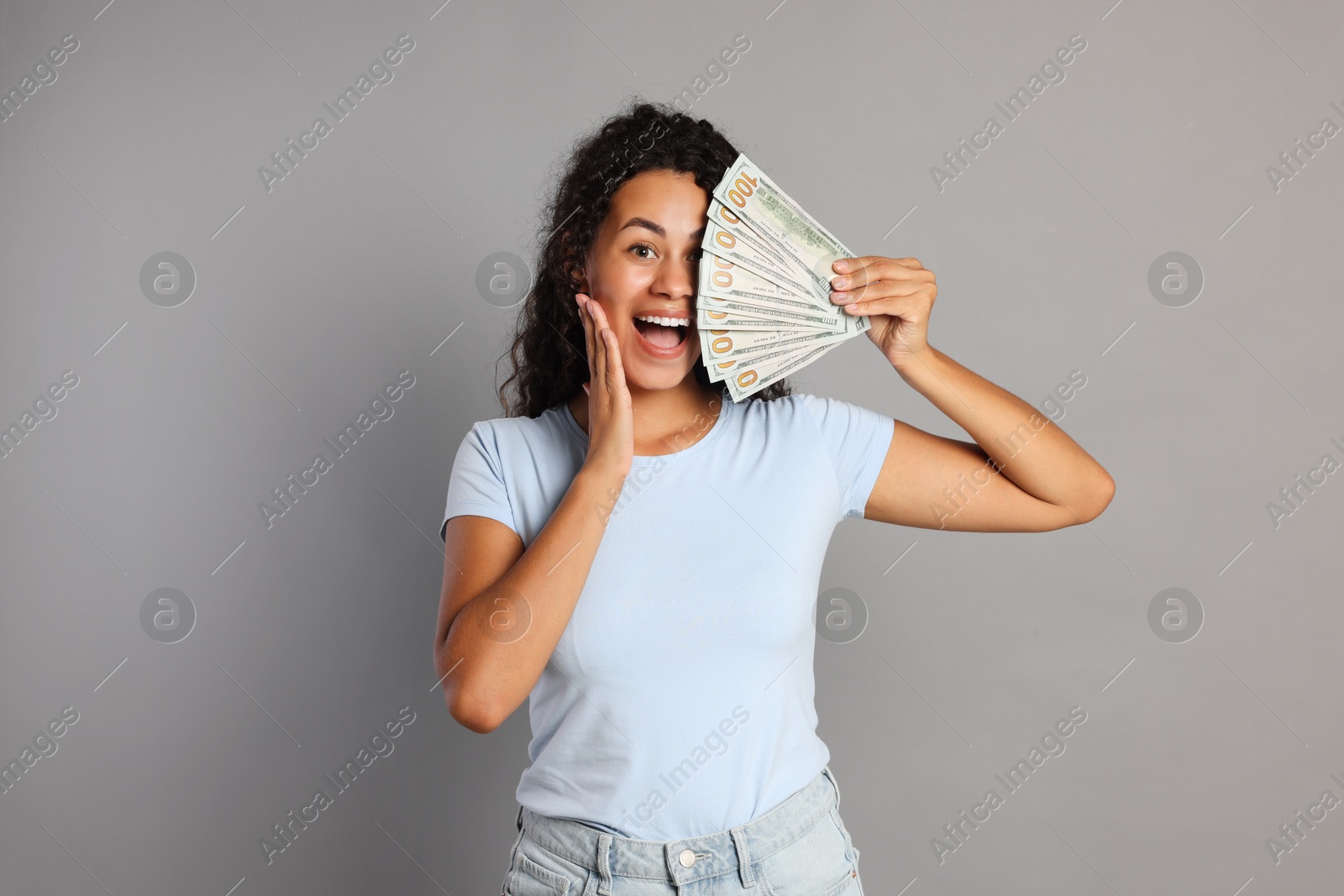 Photo of Happy woman with dollar banknotes on grey background