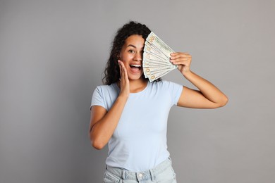 Happy woman with dollar banknotes on grey background