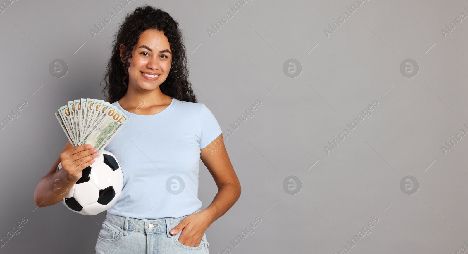 Photo of Happy woman with money and soccer ball on grey background, space for text