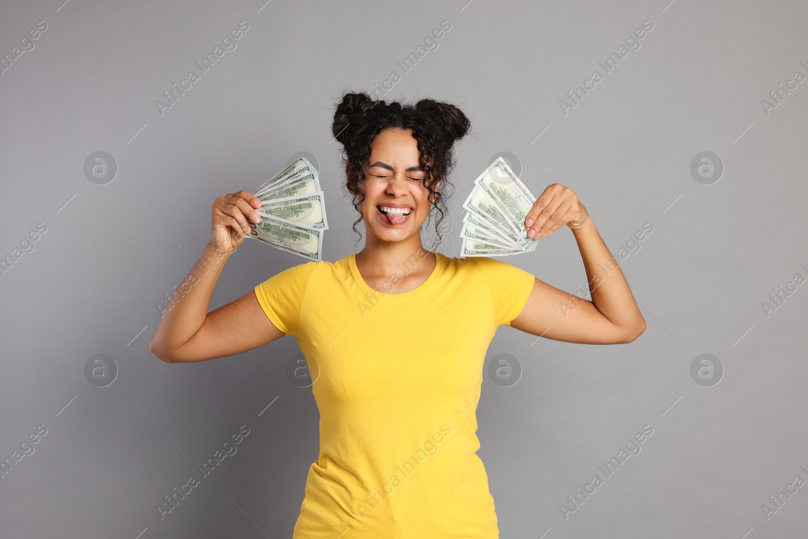 Photo of Happy woman with dollar banknotes on grey background