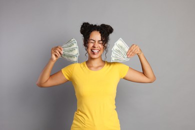 Photo of Happy woman with dollar banknotes on grey background