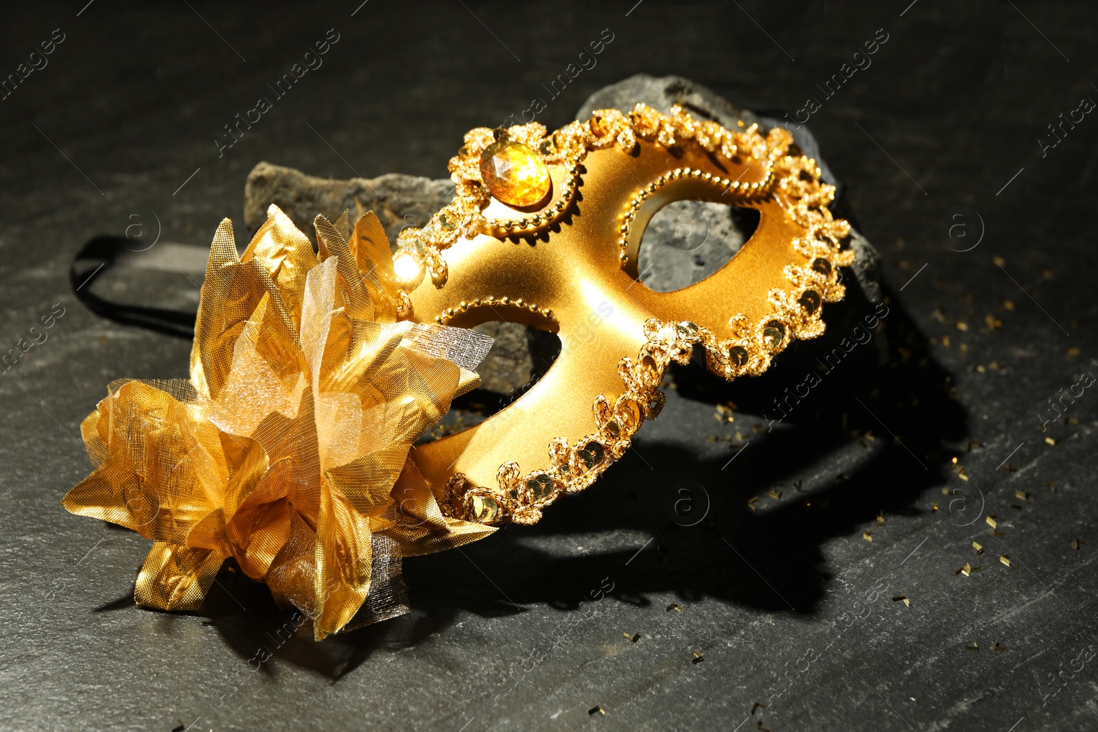 Photo of Beautiful golden carnival mask on grey textured table