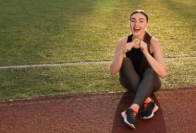 Photo of Happy winner with golden medal at stadium. Space for text