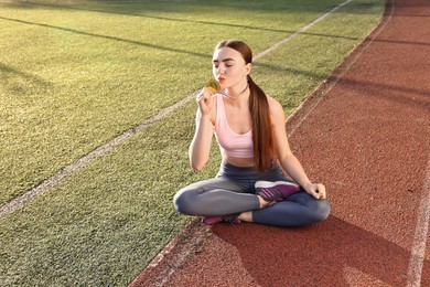 Winner kissing her golden medal at stadium on sunny day. Space for text