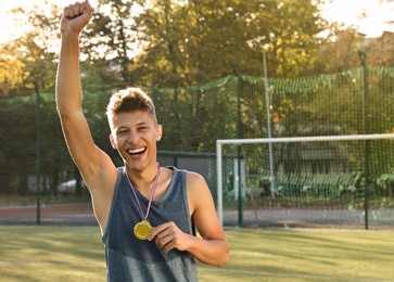 Photo of Happy winner with golden medal at stadium. Space for text