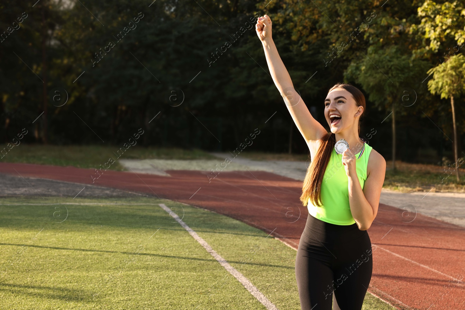 Photo of Happy winner with silver medal at stadium. Space for text