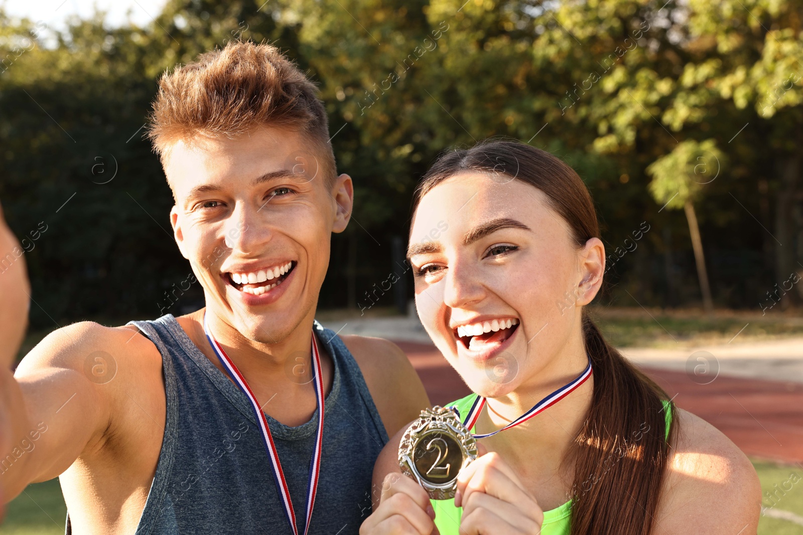 Photo of Happy winners with medals taking selfie at stadium