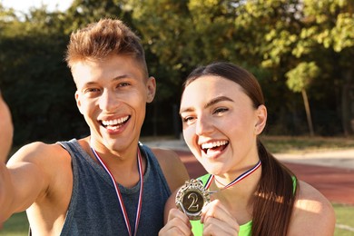 Photo of Happy winners with medals taking selfie at stadium