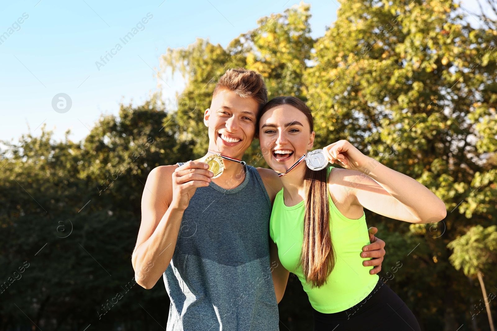 Photo of Happy winners with medals outdoors on sunny day