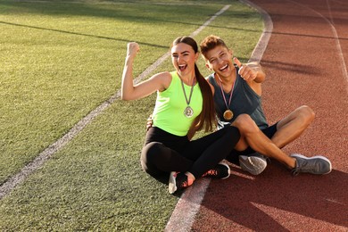 Photo of Happy winners with medals sitting at stadium. Space for text