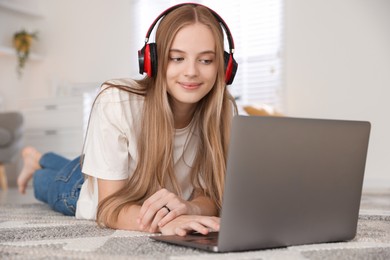 Photo of Teenage girl in headphones using laptop at home