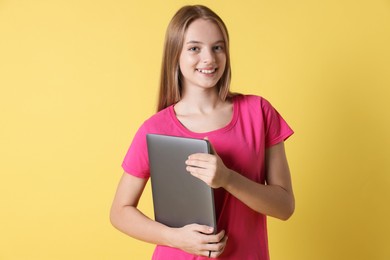 Teenage girl with laptop on yellow background