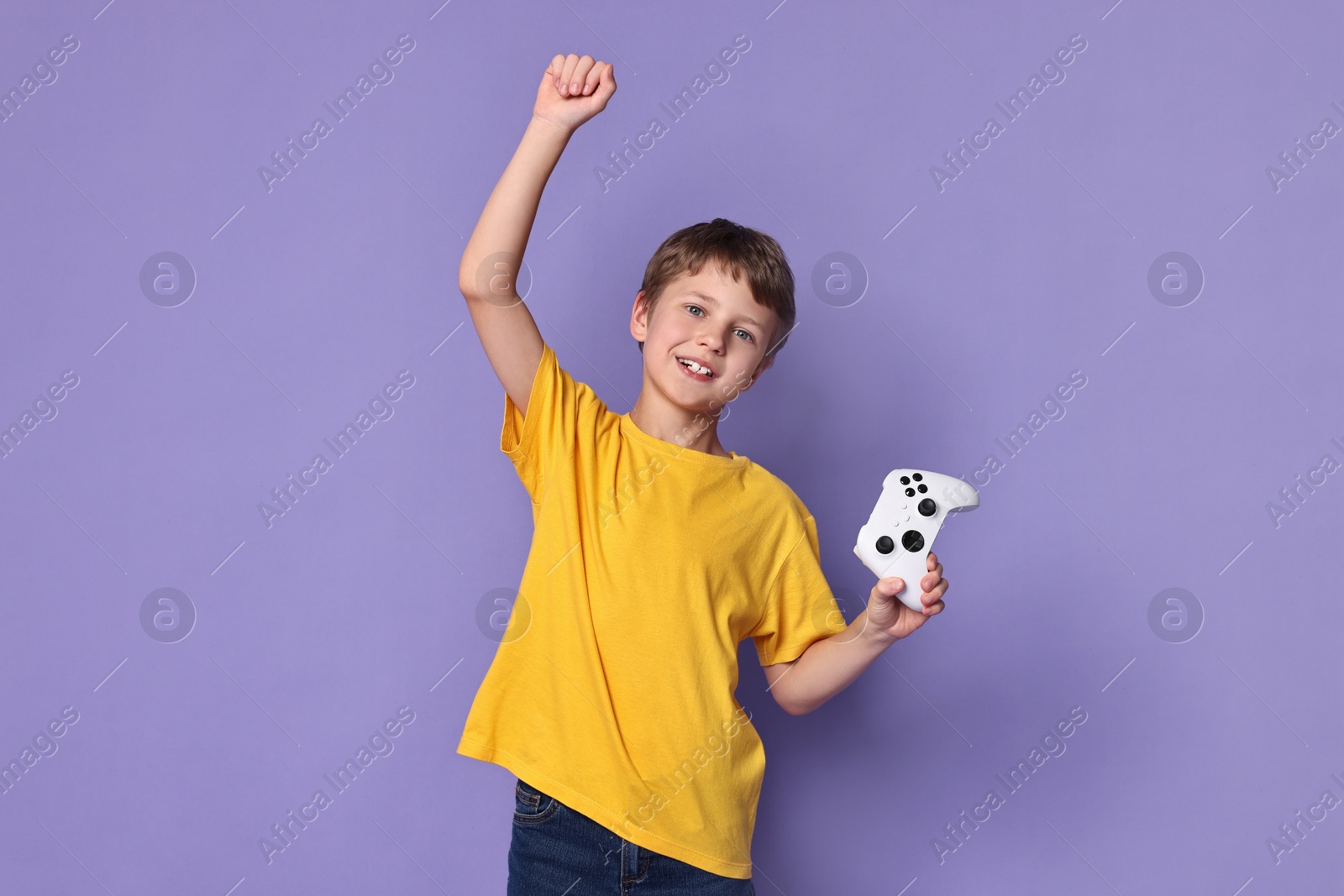 Photo of Happy little boy with controller on purple background