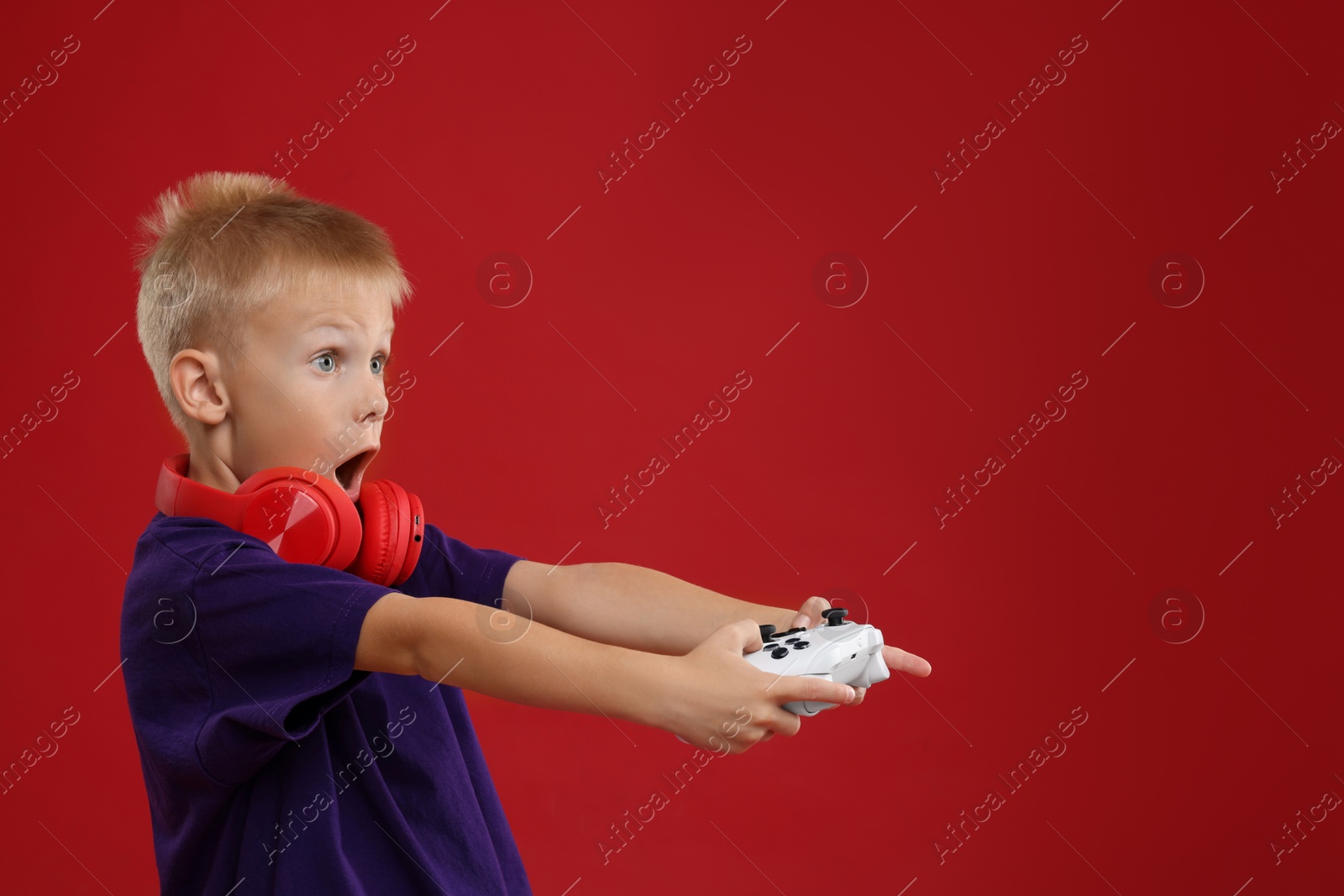 Photo of Cute little boy playing video game with controller on red background. Space for text