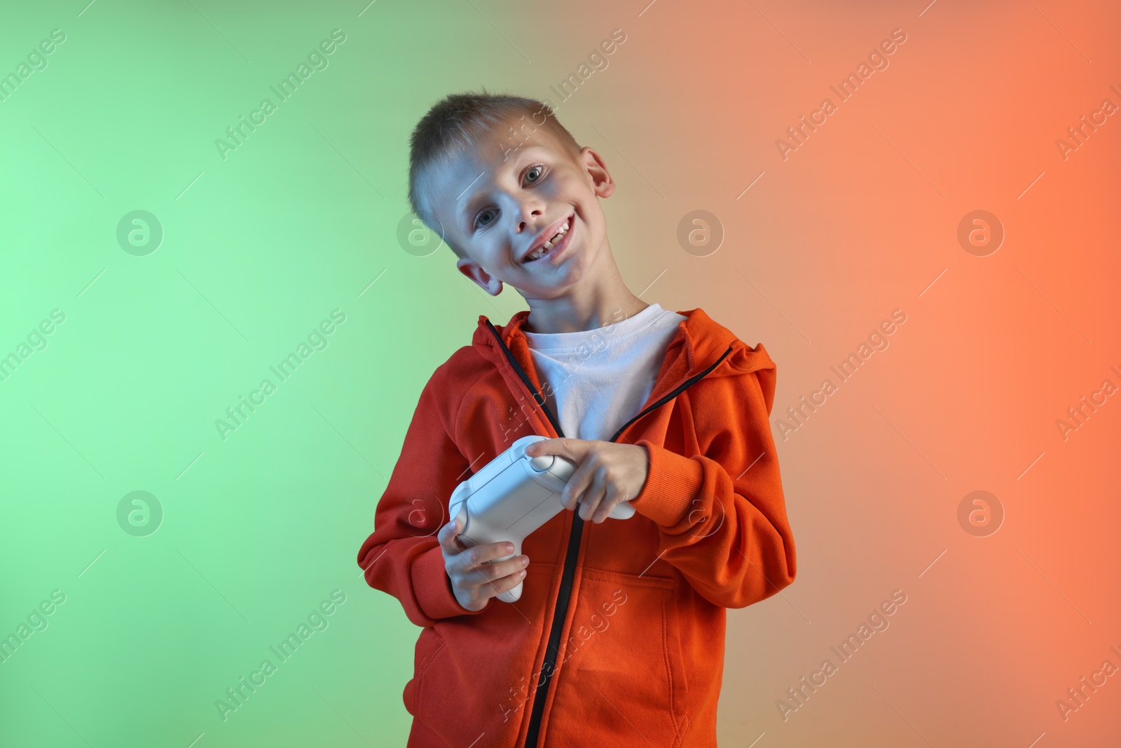 Photo of Happy little boy playing video game with controller on color background