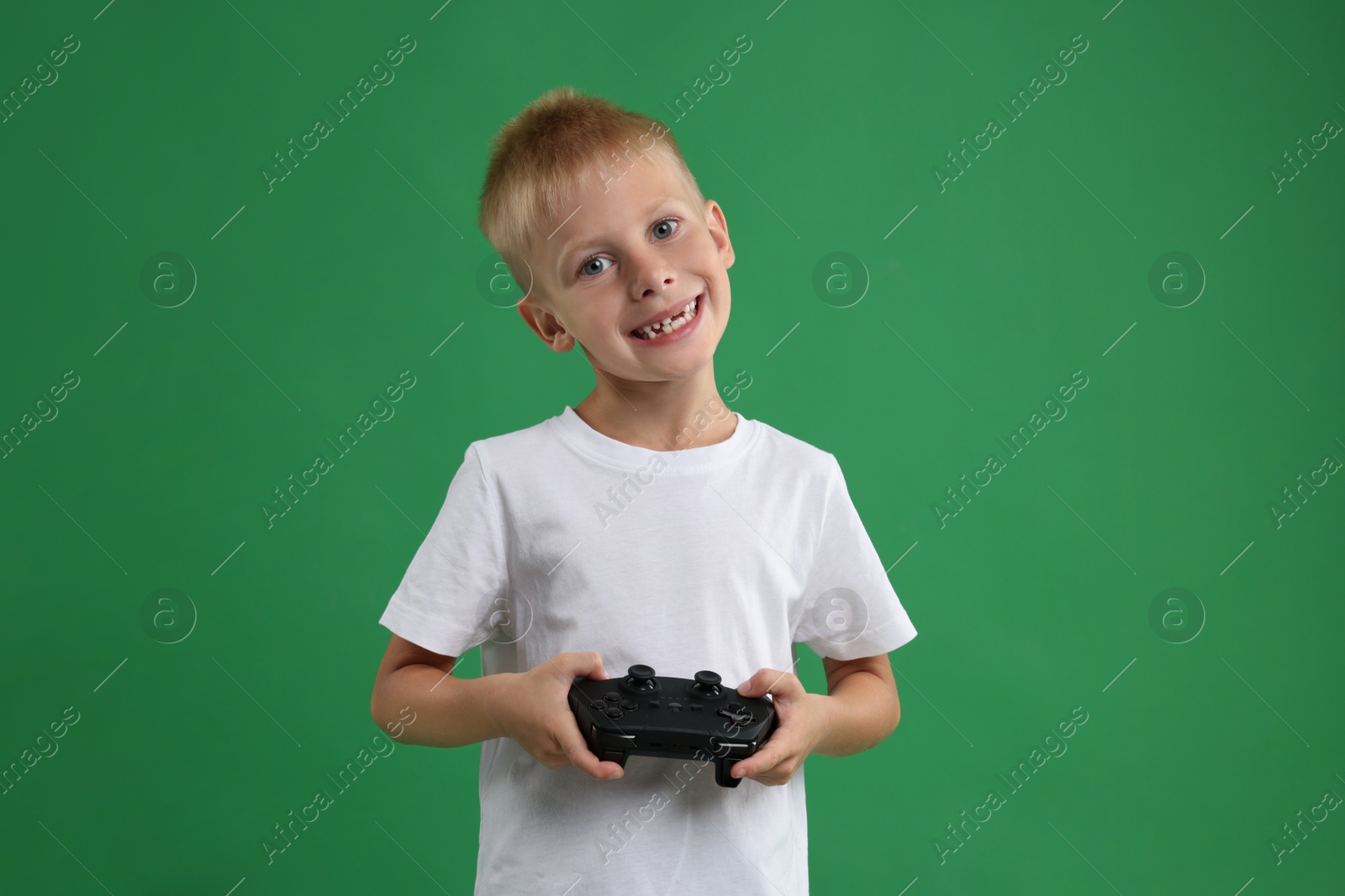 Photo of Happy little boy playing video game with controller on green background