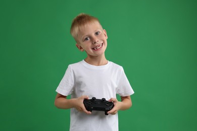 Happy little boy playing video game with controller on green background