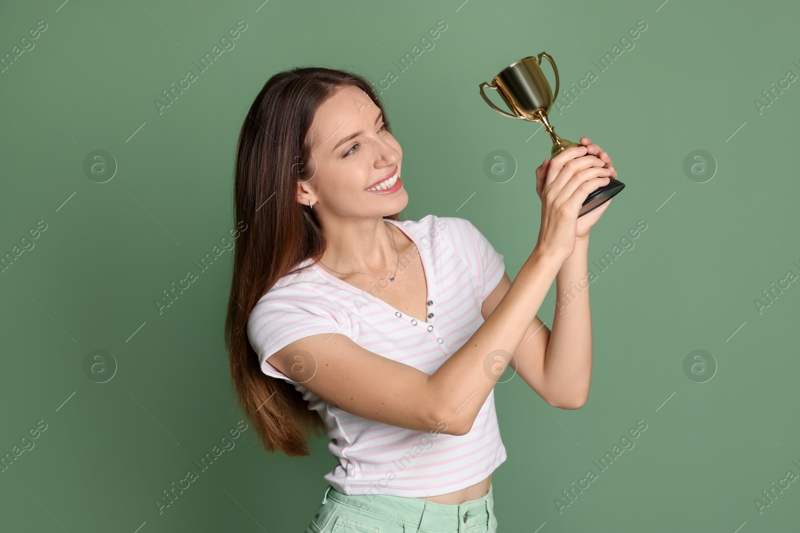 Photo of Happy winner with gold trophy cup on green background